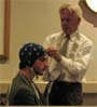 Dr Arenander adjusting the brain wave cap on the head of a young man
